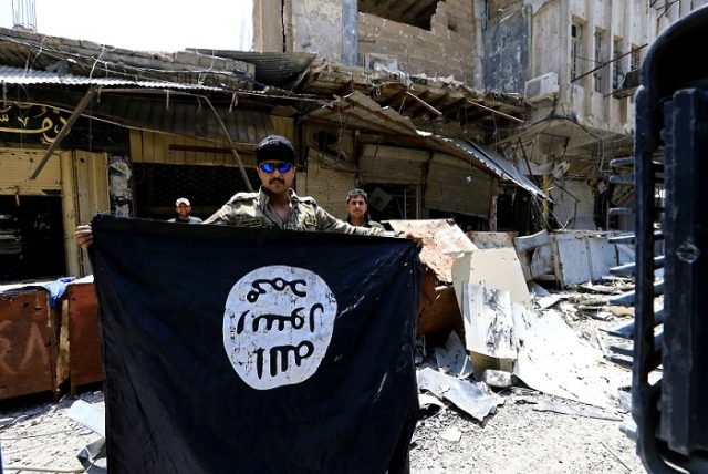 A member of the Emergency Response Division holds an Islamic State militants flag in the Old City of Mosul