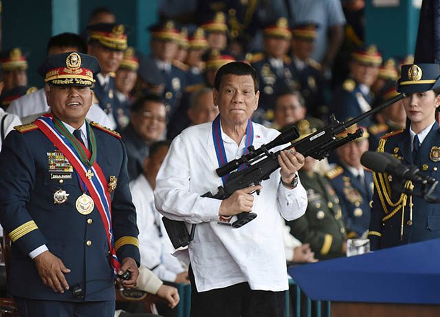 Philippine President Rodrigo Duterte holds a Galil sniper rifle next to outgoing Philippine National Police Chief Ronald Bato Dela Rosa during the National Police chief handover ceremony in Camp Crame