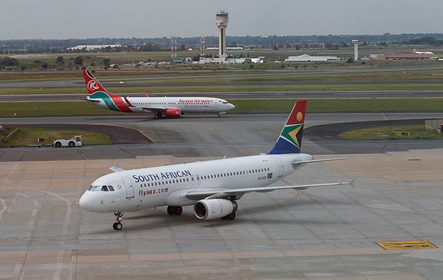 A South African Airways Airbus A320 aircraft arrives as a Kenya Airways Boeing 737 aircraft prepares to take off at the OR Tambo International Airport in Johannesburg