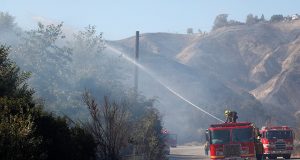 Firefighter sprays water from a fire truck