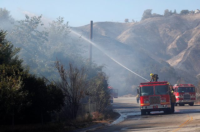 Firefighter sprays water from a fire truck