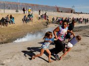 A migrant family runs away from tear gas
