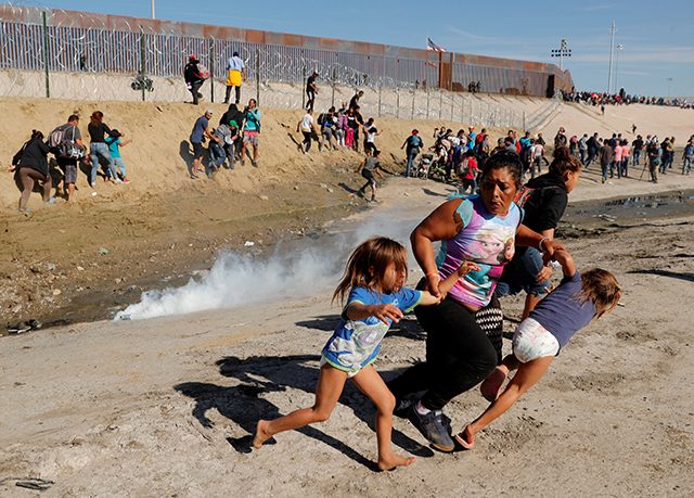 A migrant family runs away from tear gas