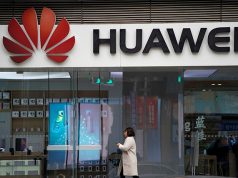 A woman walks by a Huawei logo at a shopping mall in Shanghai