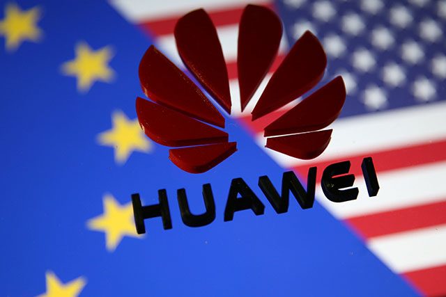 A 3D printed Huawei logo is placed on glass above displayed EU and US flags in this illustration