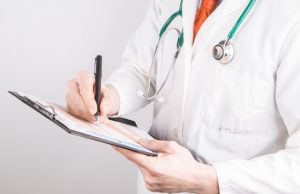 Doctor writing in clipboard