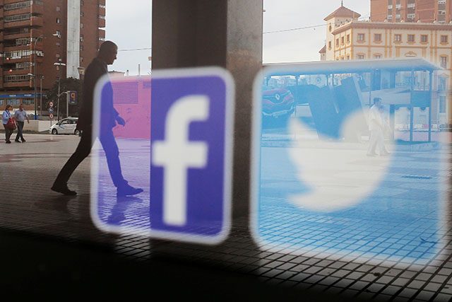 Facebook and Twitter logos are seen on a shop window in Malaga