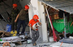 A rescuer carries a search dog