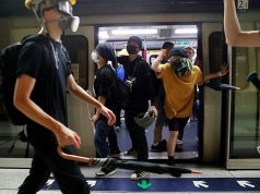 Protesters hold the door of a Mass Transit Railway (MTR) subway to allow more protesters to board and retreat, after a protest against police violence in Hong Kong