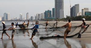 Vietnamese fishermen pull the fishnets on a beach in Da Nang city