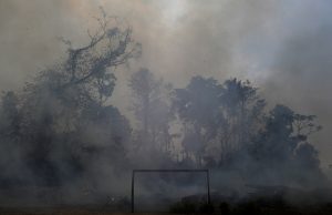 A fire burns a tract of Amazon jungle as it is cleared by loggers and farmers behind a soccer field near Porto Velho