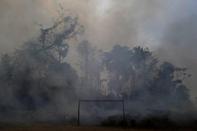 A fire burns a tract of Amazon jungle as it is cleared by loggers and farmers behind a soccer field near Porto Velho