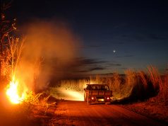 A fire burns a tract of the Amazon jungle as a truck goes by, in Areoes, Mato Grosso state