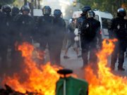 Riot police officers stand next to a burning barricade during a protest urging authorities to take emergency measures against climate change, in Paris