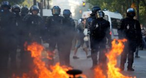 Riot police officers stand next to a burning barricade during a protest urging authorities to take emergency measures against climate change, in Paris