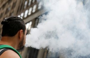 A man uses a vape as he walks on Broadway in New York City