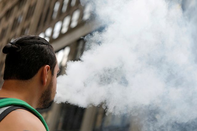 A man uses a vape as he walks on Broadway in New York City