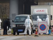 Workers in protective suits are seen at a checkpoint near a farm where African swine fever was detected