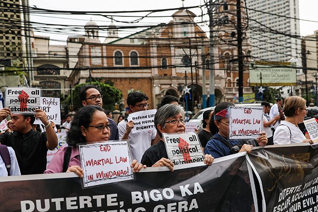 Filipino activists hold placards calling for the end of Martial Law in Mindanao region during a rally held in observance of Human Rights Day in Manila