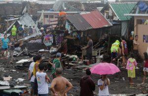 Residents stand among their damaged houses