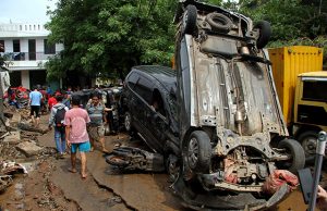 People pass vehicles damaged by floods after heavy rains in Bekasi, near Jakarta