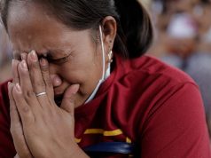 A woman displaced by Taal Volcano's eruption becomes emotional as she prays during a Catholic mass in an evacuation center