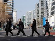 China to allow in U.S. health experts as virus shows no sign of slowing Security personnel wearing masks cross a road at the Financial Street in central Beijing