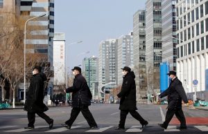 Security personnel wearing masks cross a road at the Financial Street in central Beijing