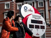 Here’s how to use ‘COVID-19’ properly, according to AP Stylebook A couple wearing protective face masks, following an outbreak of the coronavirus, walk past the big Omega One-Year Countdown clock for the opening ceremony of the Tokyo 2020 Olympic outside of Tokyo Station in Tokyo