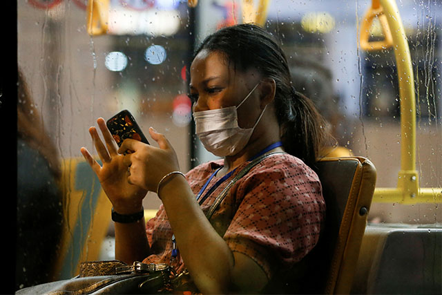 Person with mask using smartphone