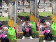 Young boy cradles his toddler sister while mom sells eggs on the street of Bohol